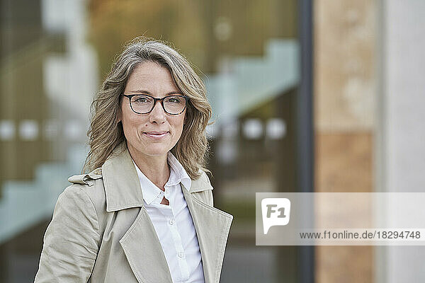 Confident businesswoman wearing eyeglasses outside building