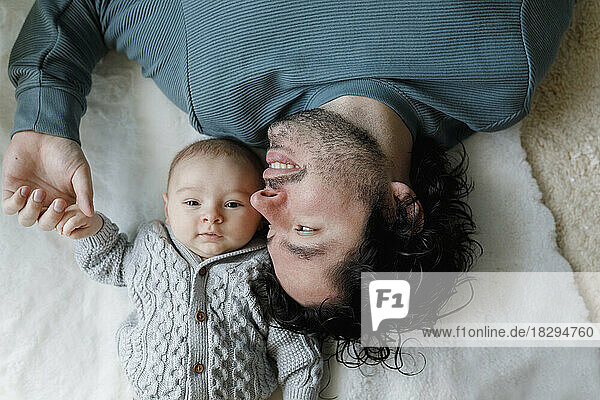 Happy father lying on bed with baby boy at home