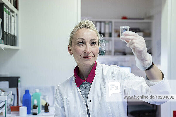 Lächelnder Wissenschaftler untersucht Flüssigkeit im Labor