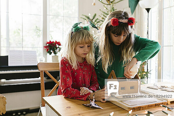 Girls making gingerbread house together at home