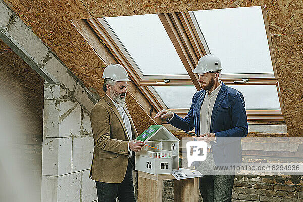 Architect explaining colleagues about model house at construction site