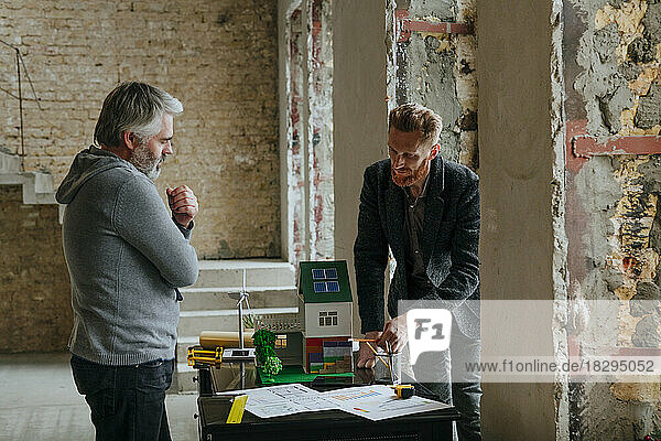 Businessman showing model house to customer at construction site