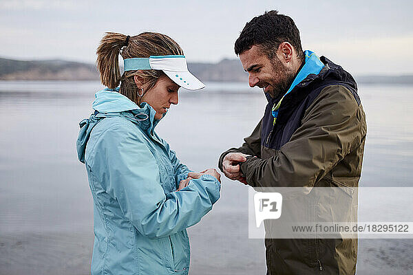 Couple setting smart watch before running at beach
