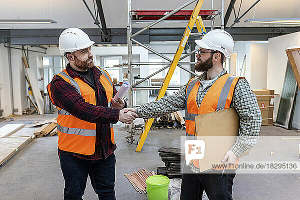 Young engineers shaking hands with each other at construction site