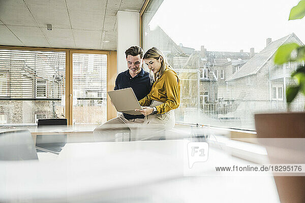 Young businessman with businesswoman working on laptop in office