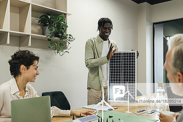 Junger Geschäftsmann diskutiert mit Kollegen im Büro über Solarpanel