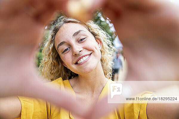 Happy young woman making heart shape with hands