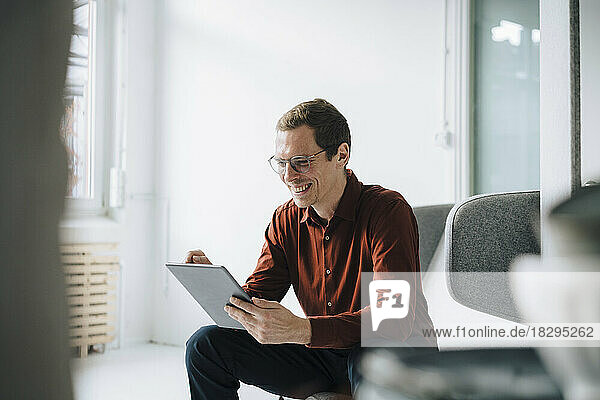 Happy businessman using tablet PC in office