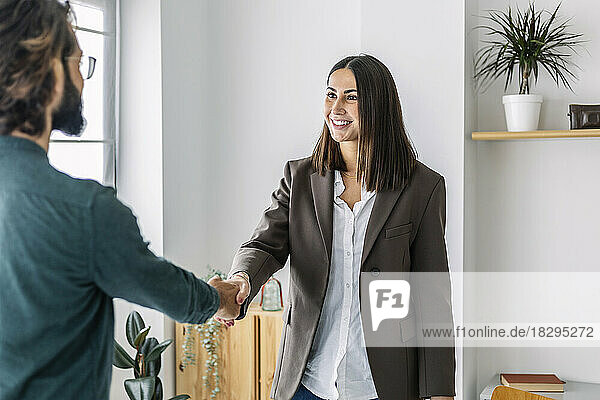 Smiling recruiter shaking hands with candidate in office