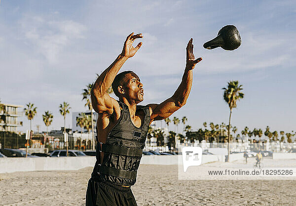 Man catching and exercising with kettlebell on beach