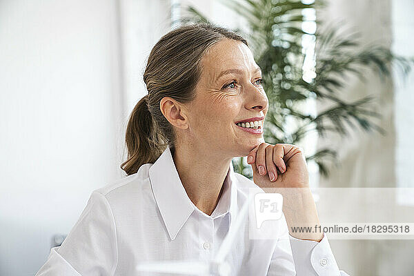 Thoughtful mature businesswoman with hand on chin in office