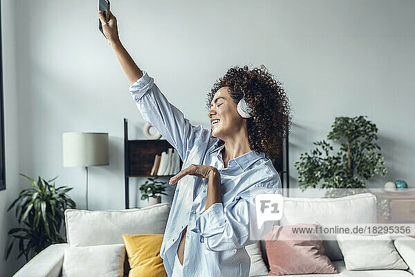 Frau gestikuliert und genießt es  zu Hause Musik über Kopfhörer zu hören