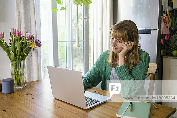 Smiling freelancer using laptop on table at home