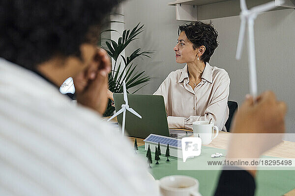 Businesswoman with colleague sitting at table in office