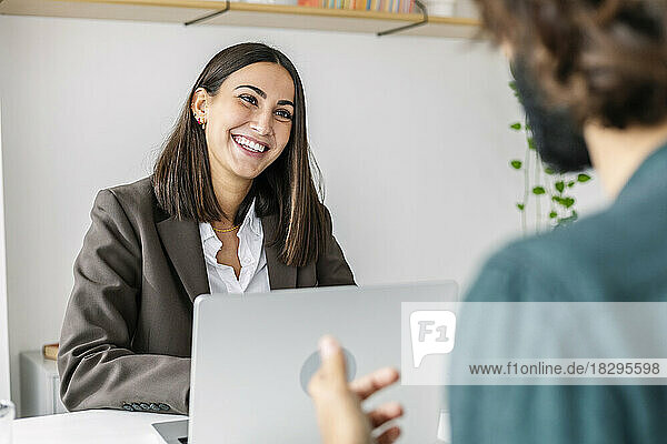 Happy recruiter interviewing candidate at desk in office