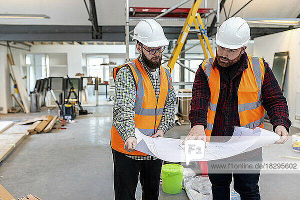 Engineer having discussion over blueprint with colleague at construction site
