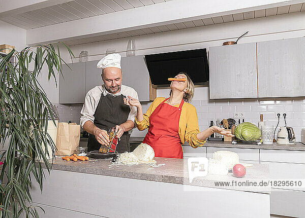 Couple wearing aprons phaving fun in kitchen at home