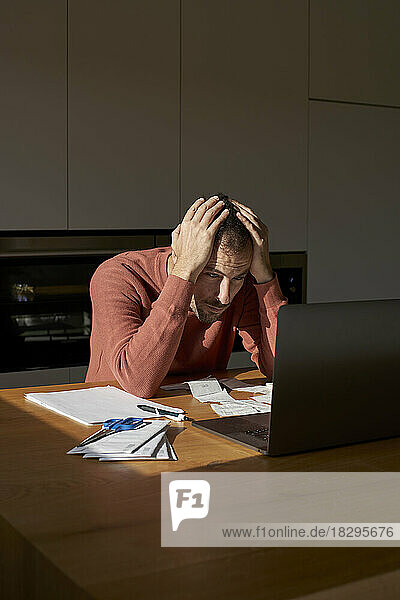 Stressed man with head in hands sitting at desk