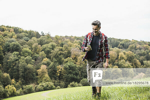 Reifer Mann benutzt Smartphone und läuft auf Gras