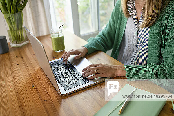 Freelancer working on laptop at table in kitchen
