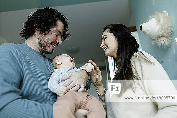 Happy mother and father playing with baby boy at home