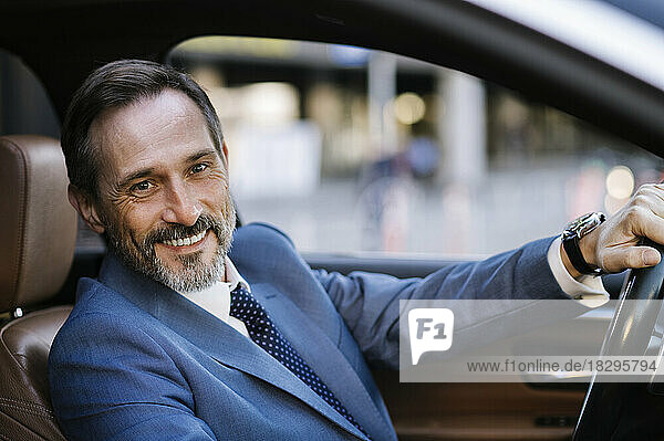 Happy mature businessman driving car