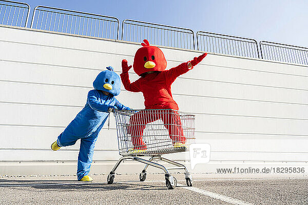 Frau im roten Entenkostüm hat Spaß mit Mann  der Einkaufswagen schiebt