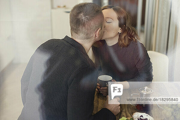 Man and woman kissing each other seen through glass window