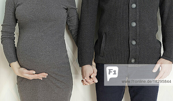 Schwangere Frau hält Händchen mit Mann