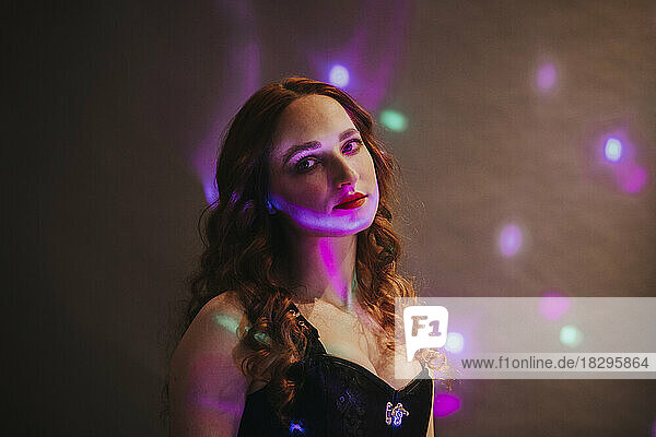 Beautiful woman with multi colored lights in front of wall