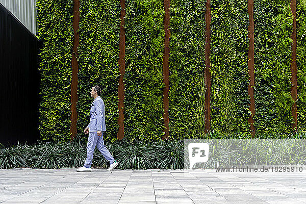 Mature businessman walking on footpath by hedge