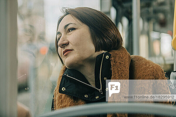 Mature woman looking through window sitting in tram