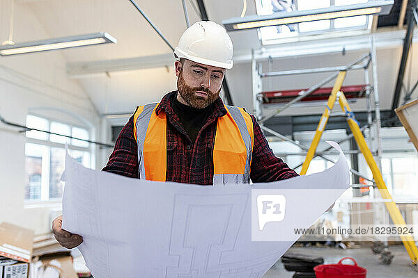 Young engineer examining blueprint at construction site