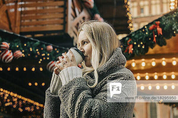 Blond woman drinking coffee at Christmas market