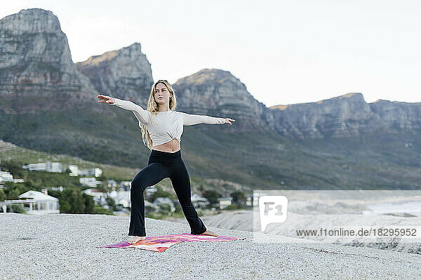 Determined woman with arms outstretched exercising in front of mountain range