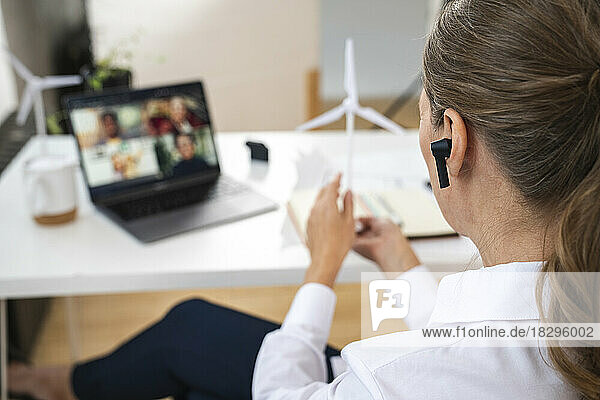 Businesswoman with in-ear headphones on video conference at office