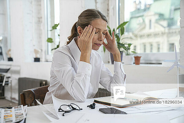 Frustrated businesswoman with head in hands sitting at office