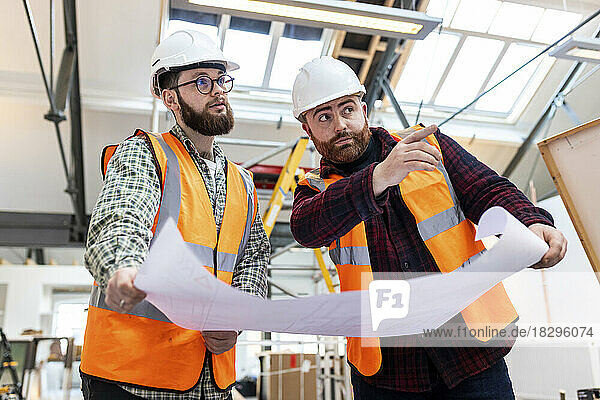 Engineer gesturing and having discussion with colleague at construction site