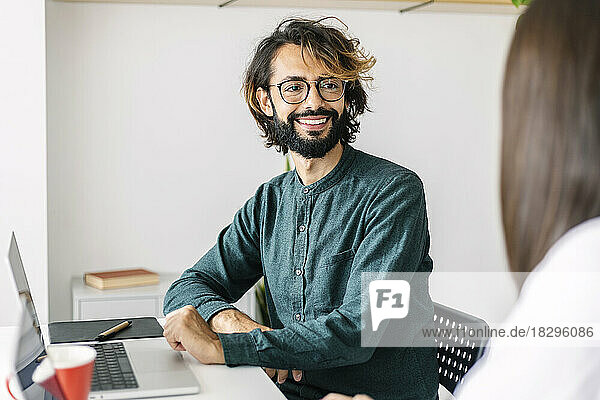 Happy businessman looking at colleague in office
