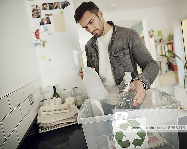Mann legt getrennten Abfall in Recyclingbox