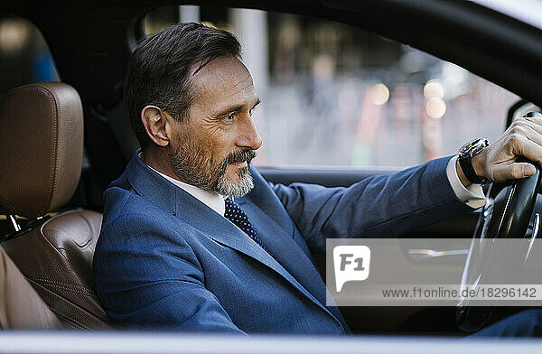 Smiling mature businessman driving car