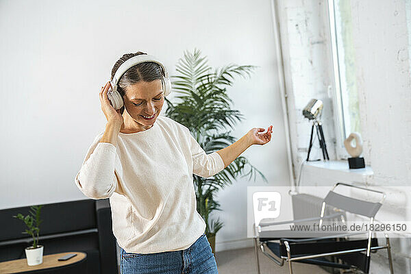 Businesswoman wearing wireless headphones enjoying in office