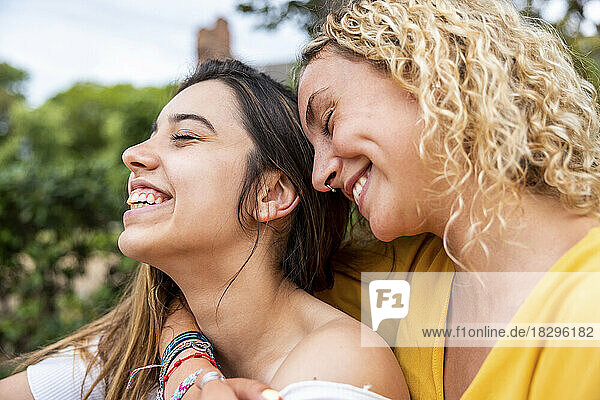 Happy lesbian young couple with eyes closed in park