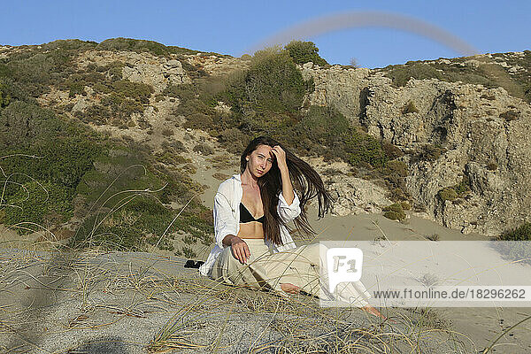 Young woman sitting on sand at beach on sunny day  Patara  Turkiye