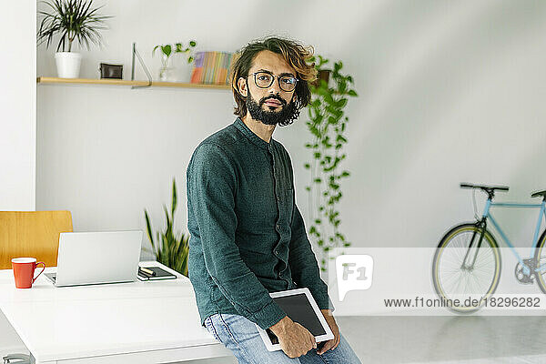 Freelancer with tablet PC leaning on desk at office