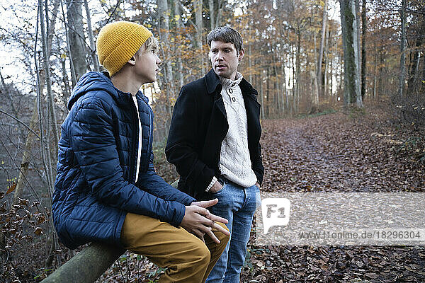 Father talking with son in autumn forest