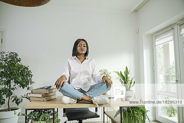 Businesswoman with eyes closed meditating on desk at home office