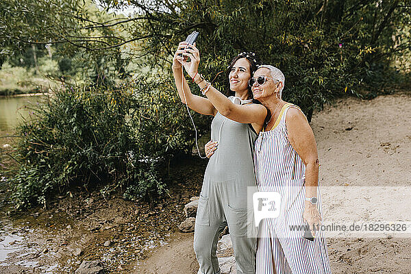 Smiling women taking selfie using smart phone at park