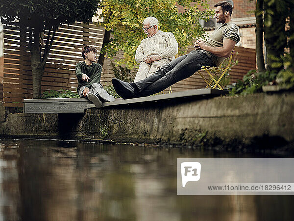 Father  son and grandson sitting at garden pond talking and relaxing