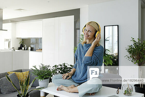 Glückliche Frau mit kabellosen Kopfhörern  die zu Hause Musik hört